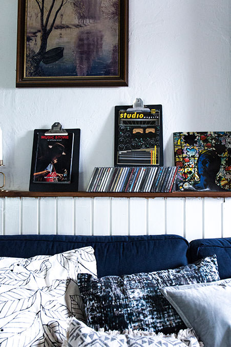 wohnzimmer-im-urban-stil-mit-vielen-kissen-cds-und-antikem-wandbild